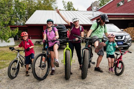 Family of 5 mountain bikers 2 adults and 3 kids pose for a silly photo.